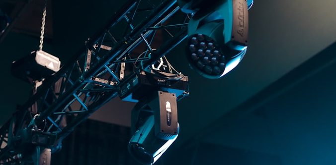 Theatre lighting installer Wales Stage lighting setup with spotlights and speakers hanging from a truss.