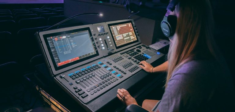 School AV systems UK Person controlling lighting equipment at a soundboard during a live event.